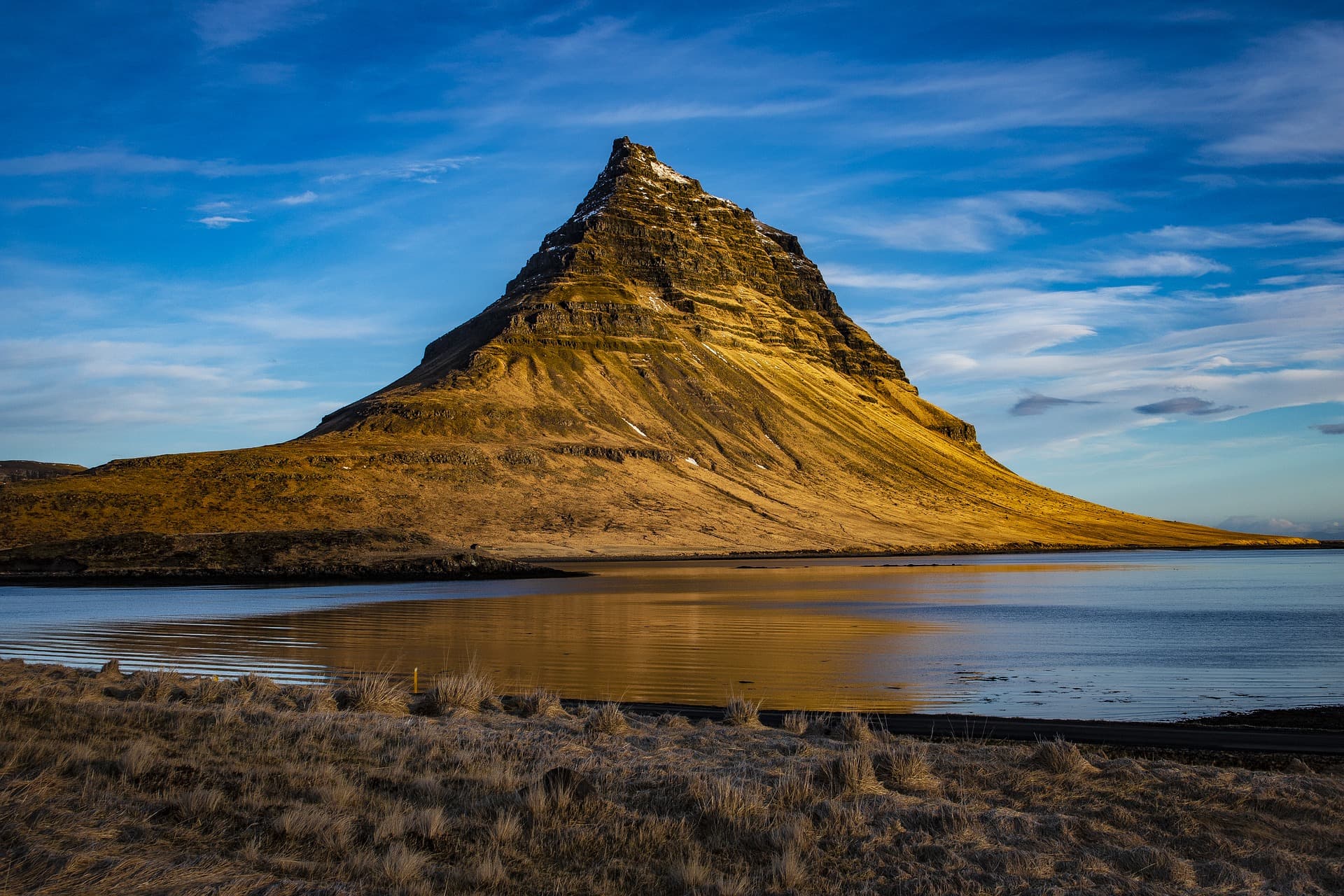 Kirkjufell Mountain in golden evening light, reflected in the water near Grundarfjörður